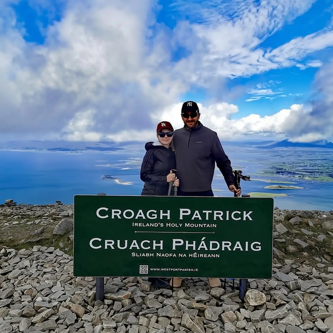 Smiling couple on top of Croagh Patrick mountain overlooking Clew Bay