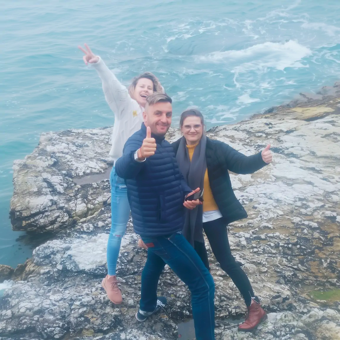 Happy group celebrating on rugged cliffs overlooking the Irish Sea