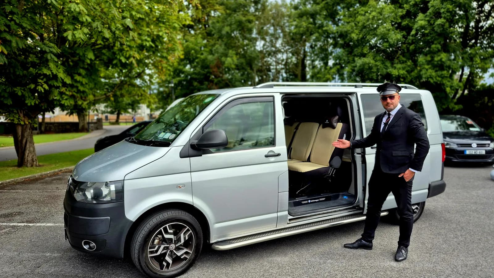 Chauffeur holding the sliding door open for passengers beside the executive van