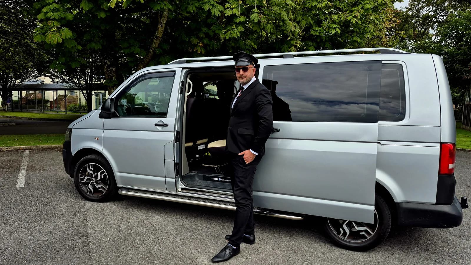 Chauffeur holding the passenger door of the executive van open for a castle-hotel arrival