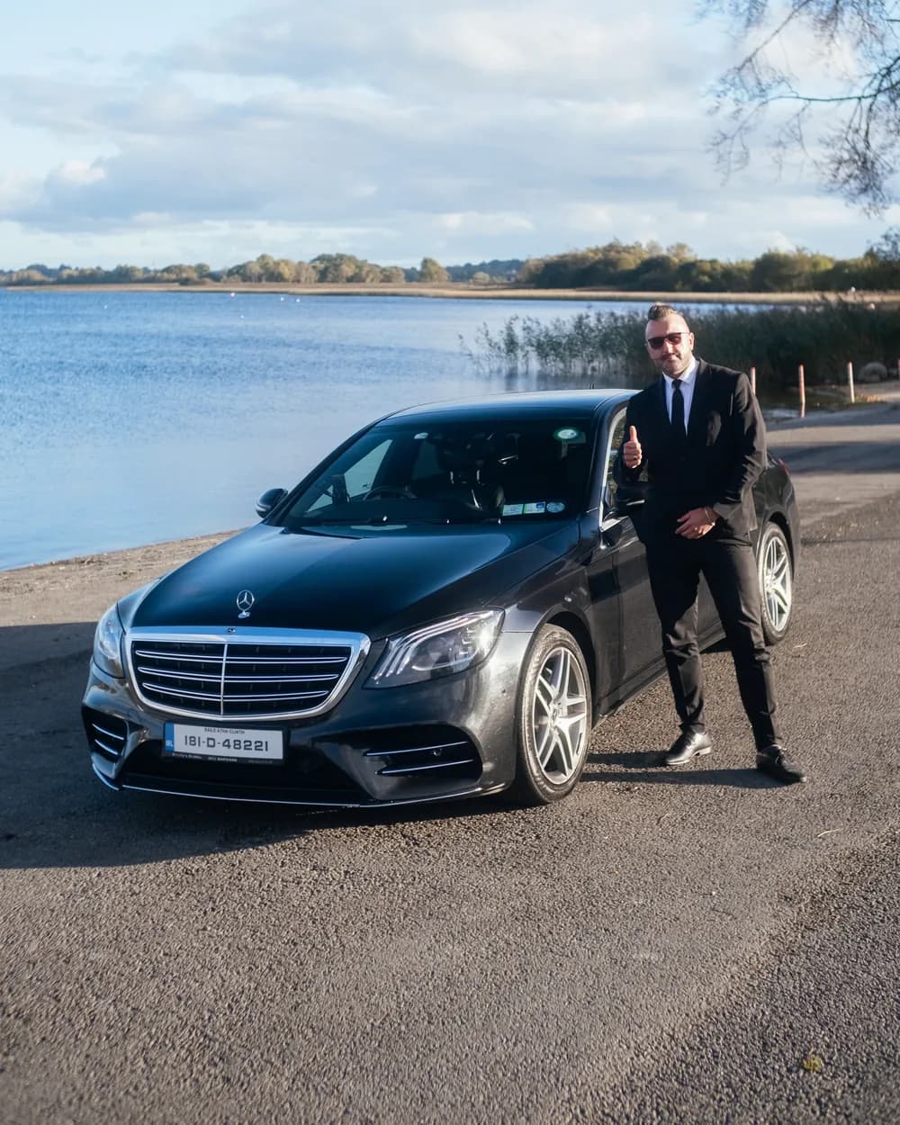 Sebastian, the chauffeur, standing beside the black Mercedes-Benz S-Class S 350d at a lakeside in Ireland