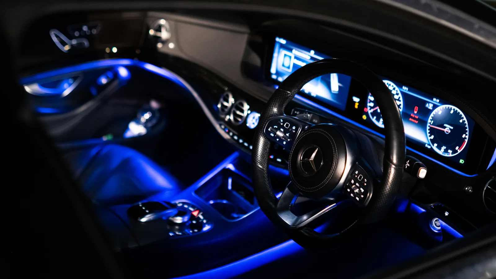 Dashboard and steering wheel of the Mercedes-Benz S-Class lit by blue ambient lighting
