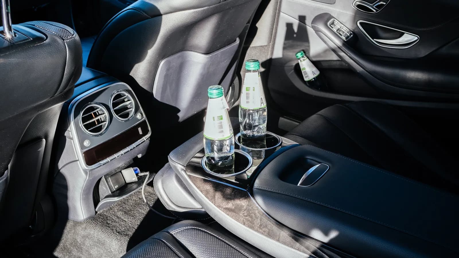 Reclining rear leather seats of the Mercedes-Benz S-Class with bottled water in the centre console