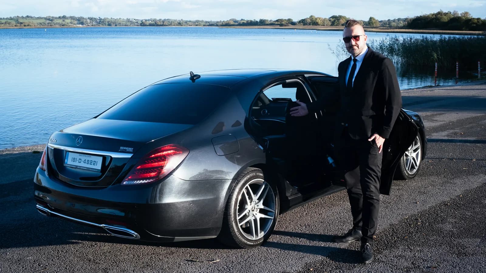 Sebastian holding the rear door of the Mercedes-Benz S-Class open for a passenger