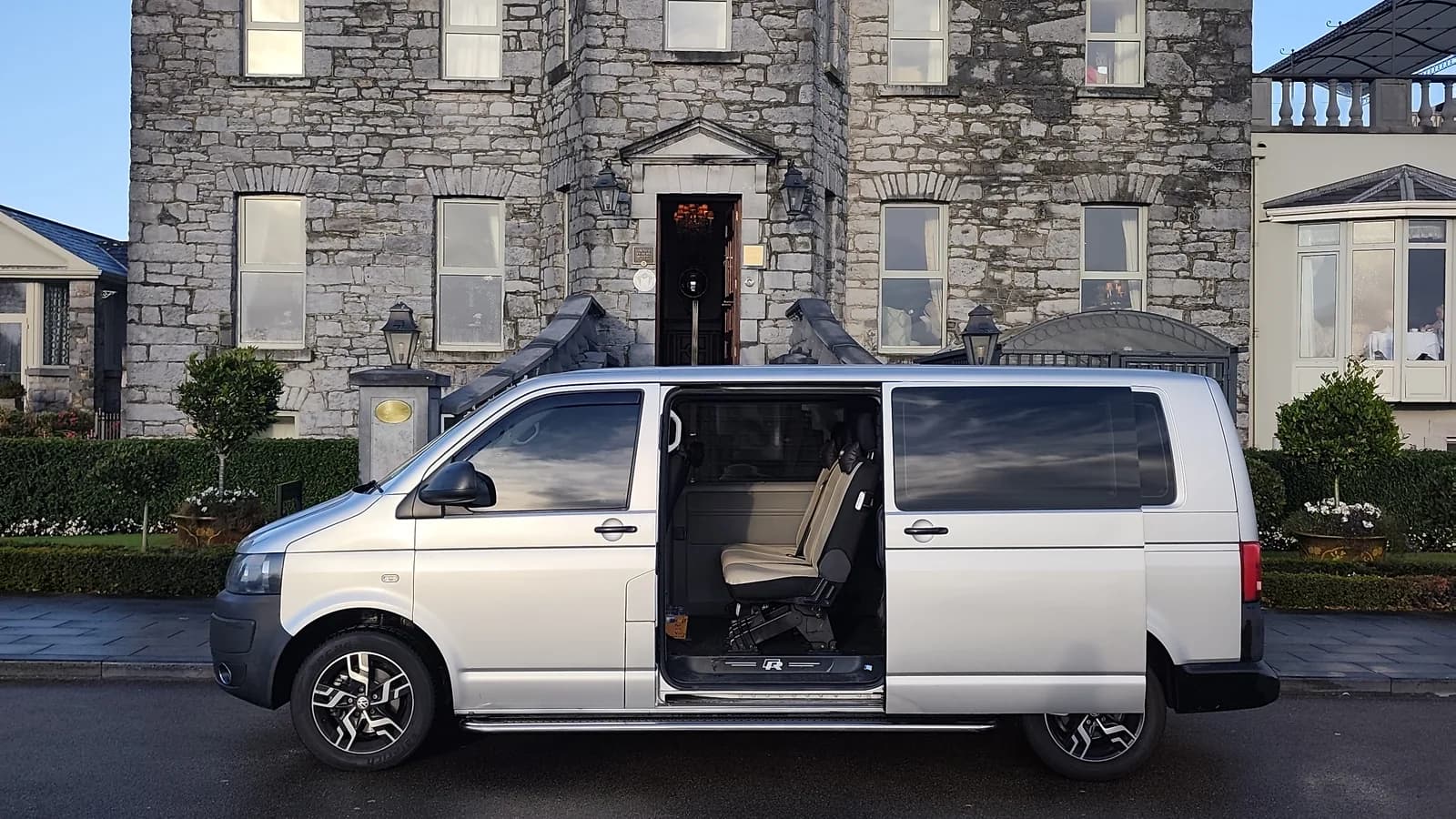 Executive transfer vehicle parked outside a historic stone building in Ireland