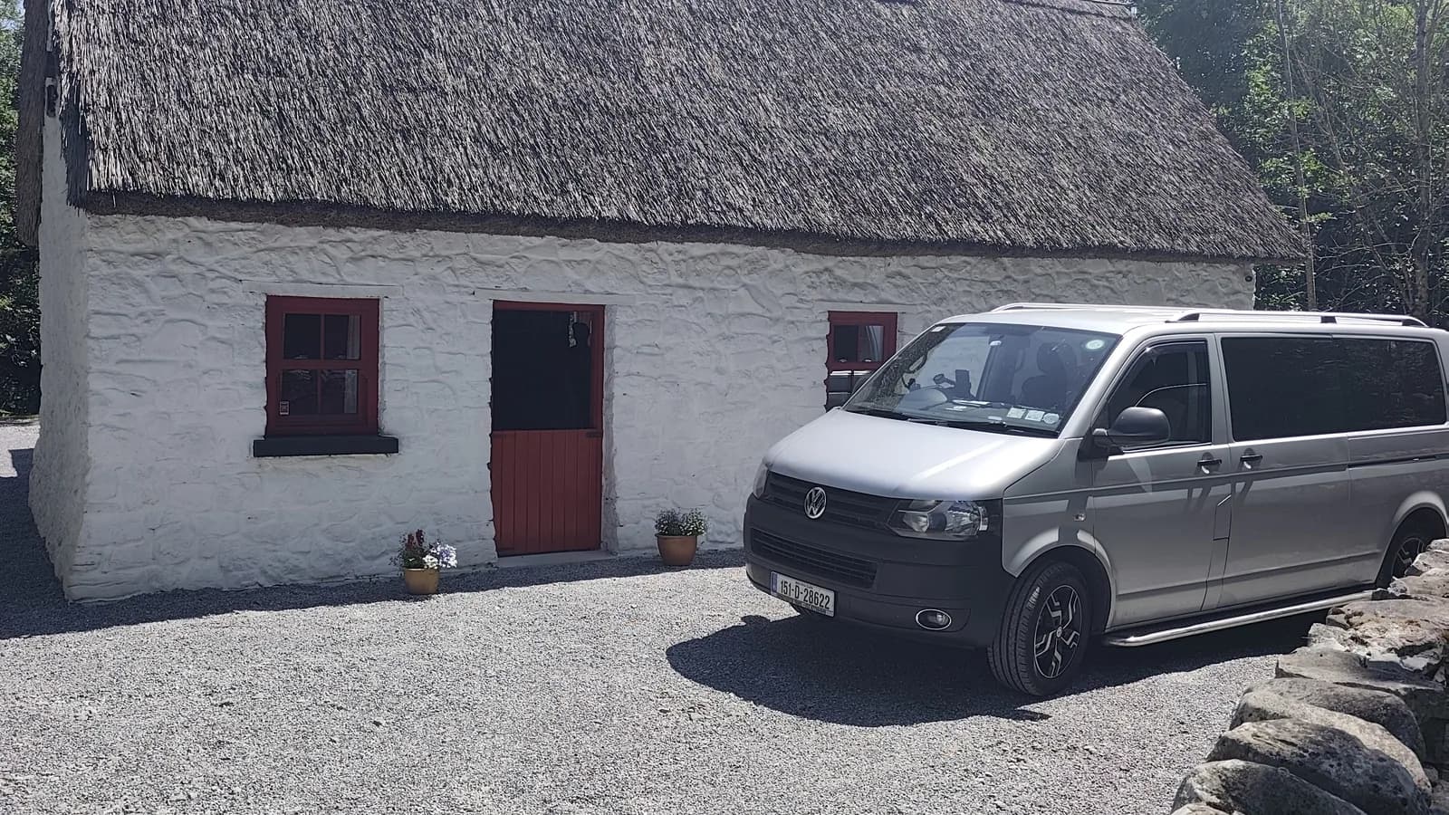 Private transfer vehicle parked outside a traditional thatched Irish cottage